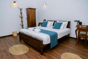 a bedroom with a large bed with blue and white pillows at Matt-Jay Villa -Baddegama in Baddegama