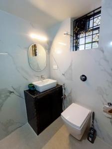 a bathroom with a sink and a toilet and a mirror at Roque's Place Goa in Betalbatim