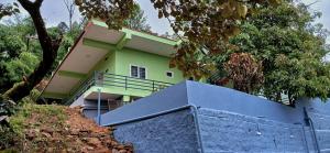 ein grünes Haus mit einem blauen Zaun davor in der Unterkunft The Town Cascade in Madikeri + 4 Fotos