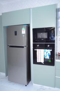 un réfrigérateur en acier inoxydable dans une cuisine à côté d'un micro-ondes dans l'établissement Jayhawk House, à Nairobi
