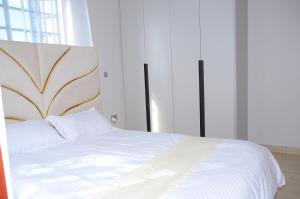 - une chambre avec un lit blanc et une grande tête de lit dans l'établissement Jayhawk House, à Nairobi