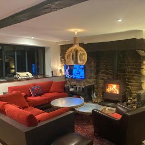 a living room with a red couch and a fireplace at Une maison à la campagne in Saint-Mars-sur-la-Futaie