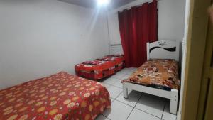 a small room with two beds and a red curtain at Casa verde temporada in São José da Barra