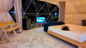 ein Schlafzimmer mit einem Bett und einem Fernseher mit einem Hut in der Unterkunft Bubble Glamping con credito Consumible! in Sosúa