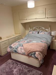 a bedroom with a bed with a floral bedspread and a vanity at King Edward house in Rhymney
