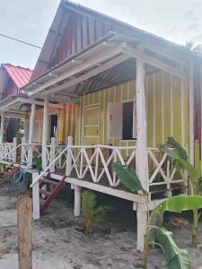a yellow house with a porch with a roof at The Two Tigers - Sok San Village in Phumĭ Kaôh Rŏng