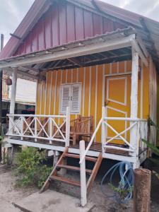 a small yellow and red house with a porch at The Two Tigers - Sok San Village in Phumĭ Kaôh Rŏng