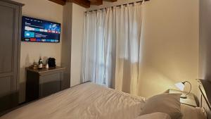 een slaapkamer met een bed en een raam met een televisie bij Locanda Arizona in Bardolino
