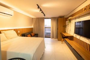 ein Hotelzimmer mit einem Bett und einem Fernseher in der Unterkunft Unity #122 - Apartamento por Carpediem in Penha