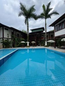 a large swimming pool with palm trees in front of a building at Recanto Verde Praia Hotel Juquehy in Juquei
