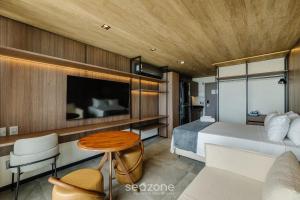 Un dormitorio con una cama, un televisor y una mesa. en NWTs - Estudios con vista lateral al mar en Maceió IV, en Maceió 72 fotos más