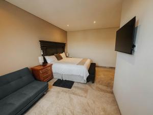 ein kleines Schlafzimmer mit einem Bett und einer Couch in der Unterkunft Suites Lassa in Ensenada