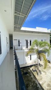 MeulabohNADA Homestay的一座白色的大楼，中间有一棵棕榈树