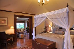 een slaapkamer met een hemelbed en een bureau bij Lake Elmenteita Serena Camp in Elmenteita