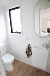 a bathroom with a toilet and a mirror at The Coconut Hut Papamoa Beach in Tauranga +14 photos