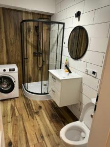 a bathroom with a shower and a toilet and a washing machine at Apartament Siedlce ul Szkolna 4 in Siedlce