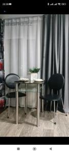 une table et deux chaises devant un rideau dans l'établissement квартира Центр, à Semey