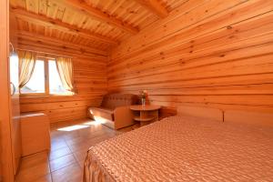 a bedroom with a bed and a chair in a wooden room at Romo sodyba in Trakai