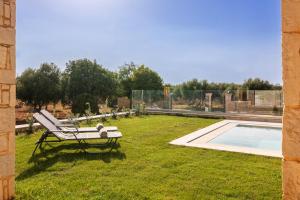 a chair sitting in the grass next to a pool at Villa Sandi with Private Pool in Hersonissos