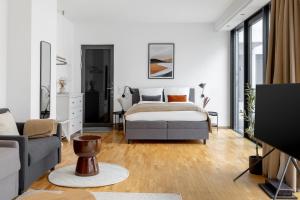a bedroom with a bed and a couch and a tv at Global Living - Design Apartment I Rathausplatz I Kitchen I Augsburg in Augsburg