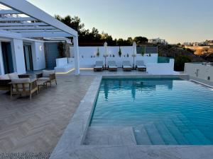a swimming pool with chairs and tables on a patio at Villa Aristoteles in Líndos