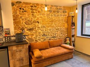 ein Sofa in einer Küche mit Steinwand in der Unterkunft BullyCosy in Bully