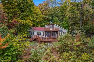 a house in the middle of a forest at Above Sleepy Hollow - Rooftop Deck, Amazing Views, Hot Tub, Pet Friendly, Screen Porch, Wifi, EV Station, Games, Trails, Wood Stove, Charcoal Grill, Lake Access, King Bed in Hedgesville