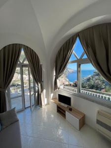 ein Wohnzimmer mit großen Fenstern und einem Sofa in der Unterkunft La Positanella - Positano bright apartment in Positano