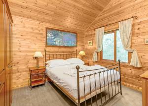 een slaapkamer met een bed in een blokhut bij Tilford Woods Lodge Retreat in Farnham