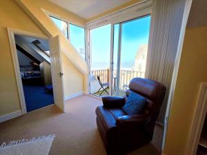 ein Wohnzimmer mit einem Stuhl und einem großen Fenster in der Unterkunft Shellsborough Penthouse in Woolacombe