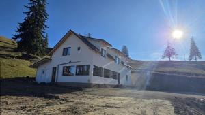 a house on a hill with the sun in the sky at Pensiunea Heaven in Dîmbovicioara +28 photos