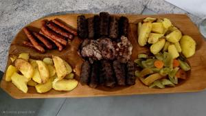 a wooden cutting board with sausage and potatoes on it at Pensiunea Heaven in Dîmbovicioara