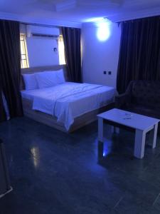 Un dormitorio con una cama, una mesa y un sofá. en Noblelite Hotels, en Gwarinpa