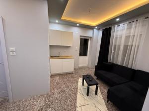 Una sala de estar con un sofá negro y una mesa. en Masal home, en Alexandroupoli