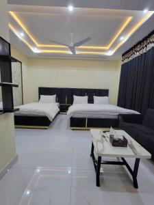 a hotel room with two beds and a couch at Airport Gateway Guesthouse in Rawalpindi +23 photos