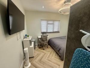 ein Schlafzimmer mit einem Bett, einem Schreibtisch und einem Waschbecken in der Unterkunft Luxurious Bedroom and Living room in a House in Romford