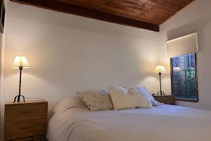 a bedroom with a bed with two lamps and a window at CosmoSur - Centro El Bolson in El Bolsón