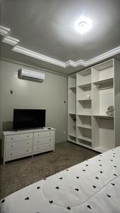 a bedroom with a bed and a tv and shelves at Família Macapá in Macapá