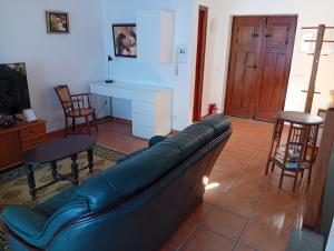 a living room with a leather couch and chairs at Casa próxima da praia fluvial in Mourão