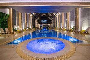 a large pool with blue water in a building at Jazz apartman Titova vila in Zlatibor