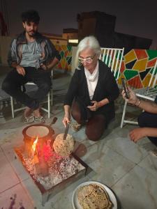斋浦尔The Pink Nest - Backpackers Abode的一位老妇人正在锅里拨弄火苗。