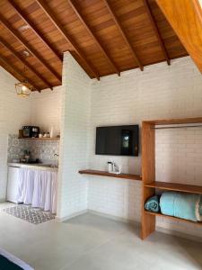 a room with a tv on a white brick wall at Chalé Colibri Verde in Santa Teresa +13 photos