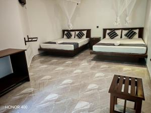 Zimmer mit 2 Betten, einem Tisch und einem TV in der Unterkunft Induwara Safari Resort in Udawalawe