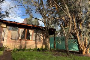 ein Haus mit einer grünen Tür neben einem Baum in der Unterkunft La Perla in El Bolsón