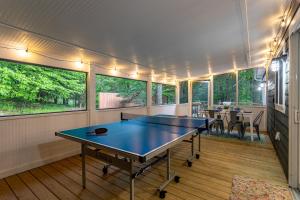 una mesa de ping pong en una habitación con ventanas en Hare & Hollow with Hot Tub & Fenced Yard, en Long Eddy