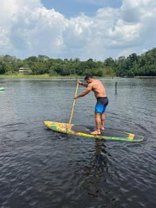 a man standing on a paddle board in the water at Ybyra Pousada de Selva in Careiro +25 photos