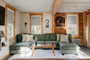 1930's Vintage Cabin Hot Tub Kohler Cabin في Jeffersonville: غرفة معيشة مع أريكة خضراء وطاولة