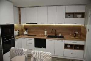 eine Küche mit weißen Schränken, einer Spüle und 2 Stühlen in der Unterkunft C&A Apartment in Goze Deltschew