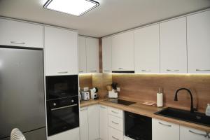 a kitchen with white cabinets and a black appliance at C&A Apartment in Gotse Delchev