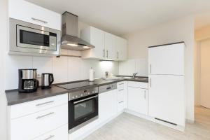a kitchen with white cabinets and a microwave at D4 Bungalow - Haus Dünenpark Königsberger Allee 12 - FERIENDOMIZIL HOLLICH in Grömitz